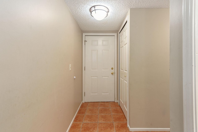 corridor featuring light tile patterned floors and a textured ceiling