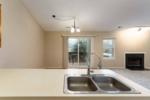 kitchen with a textured ceiling, decorative light fixtures, a notable chandelier, and sink