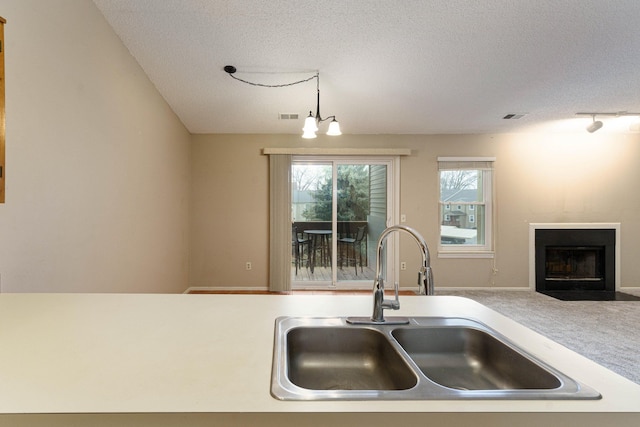 4980 Oak Hill Dr Unit 66, Waterford, MI 48329 - kitchen with a textured ceiling, a fireplace with flush hearth, light countertops, open floor plan, and carpet floors