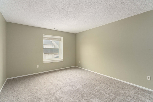 carpeted empty room featuring a textured ceiling