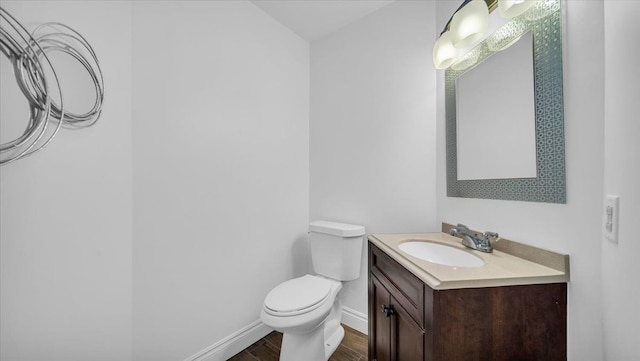 bathroom with toilet, vanity, and hardwood / wood-style flooring