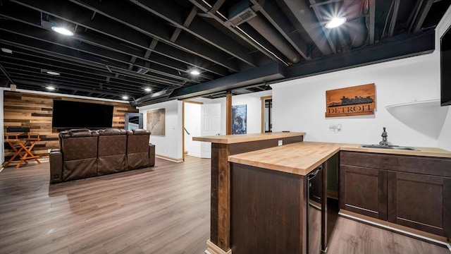 bar featuring hardwood / wood-style flooring, dark brown cabinetry, butcher block counters, and sink