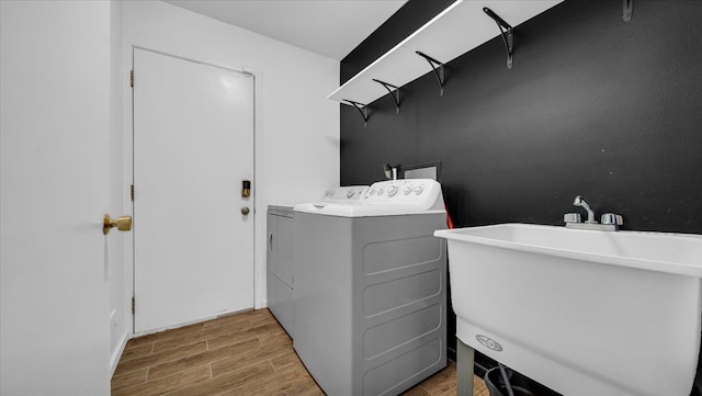 washroom with hardwood / wood-style flooring, washer and clothes dryer, and sink