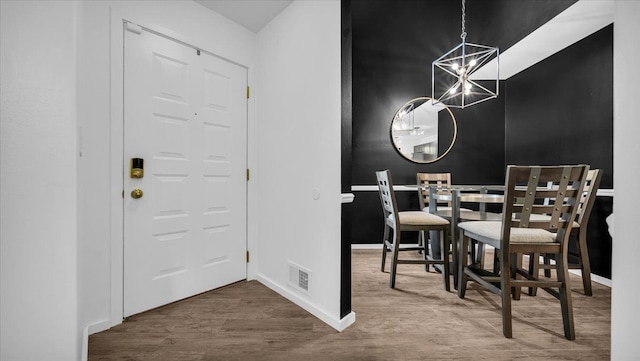 dining room featuring wood-type flooring and an inviting chandelier