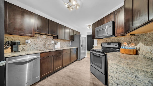 kitchen with light stone countertops, dark brown cabinetry, stainless steel appliances, and backsplash