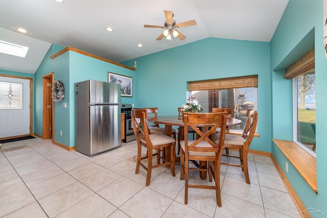 tiled dining space featuring ceiling fan and lofted ceiling with skylight