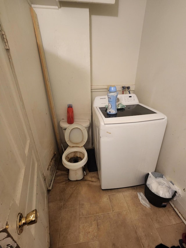 bathroom featuring tile patterned floors, toilet, and washer / dryer