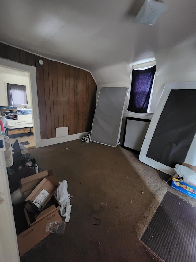 bonus room with lofted ceiling and wooden walls