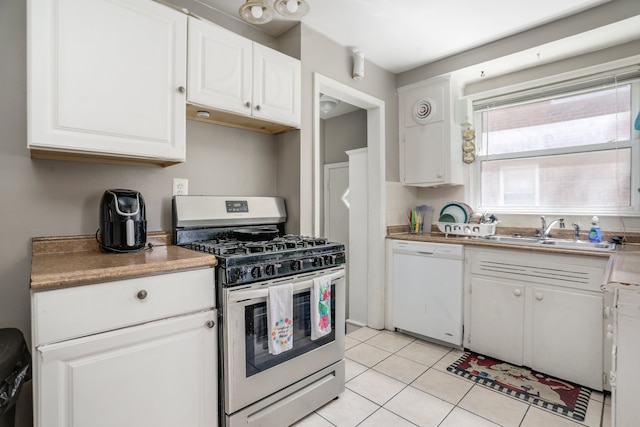 kitchen with white dishwasher, sink, white cabinets, stainless steel range with gas stovetop, and light tile patterned flooring