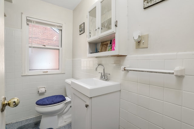 bathroom with tile patterned flooring, vanity, tile walls, and toilet