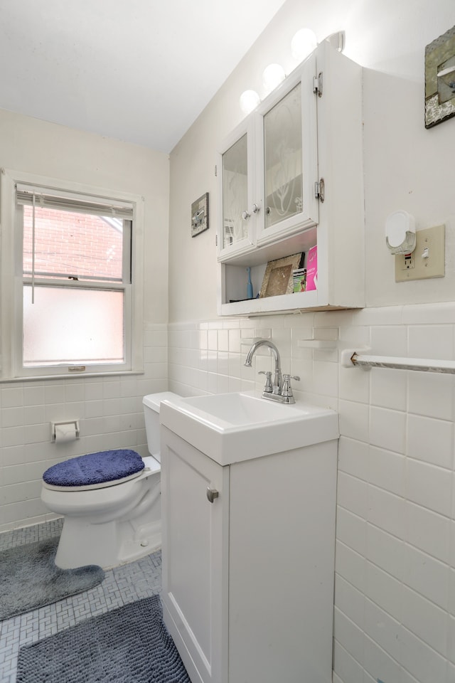 bathroom with tile patterned floors, vanity, tile walls, and toilet