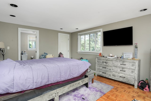 bedroom with ensuite bath, light parquet flooring, and multiple windows