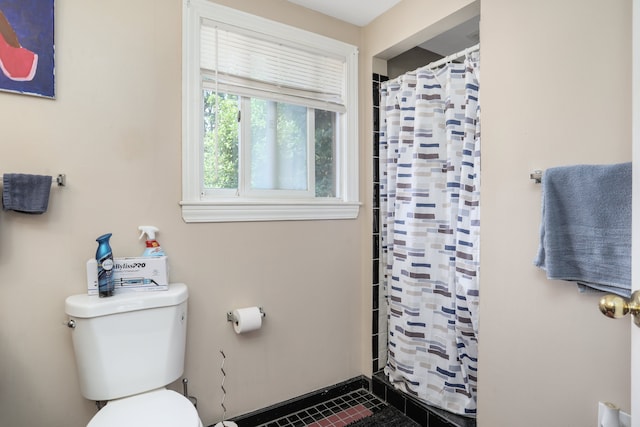 bathroom with a shower with shower curtain, toilet, and tile patterned floors