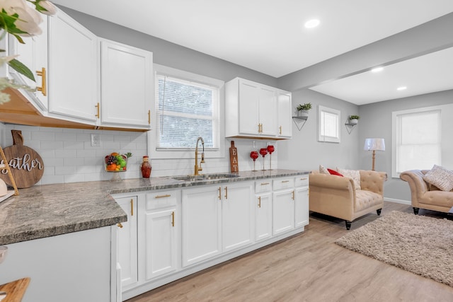 kitchen featuring a wealth of natural light, white cabinetry, sink, and light wood-type flooring