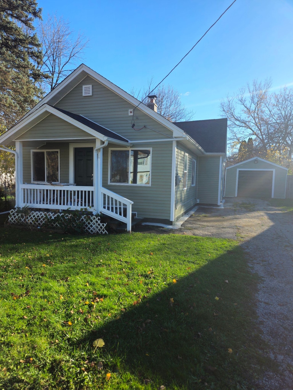 exterior space with a front yard, a porch, a garage, and an outdoor structure