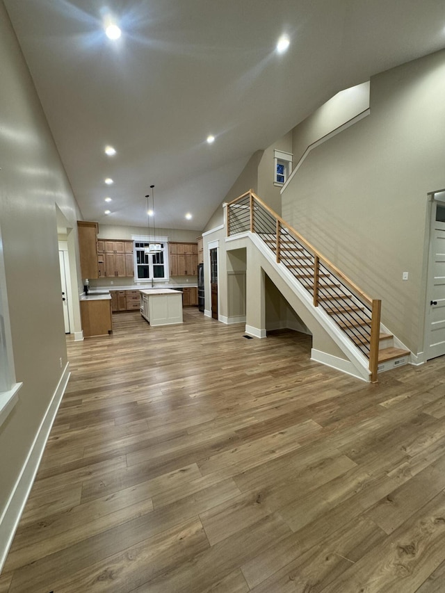 unfurnished living room with recessed lighting, stairs, baseboards, and wood finished floors