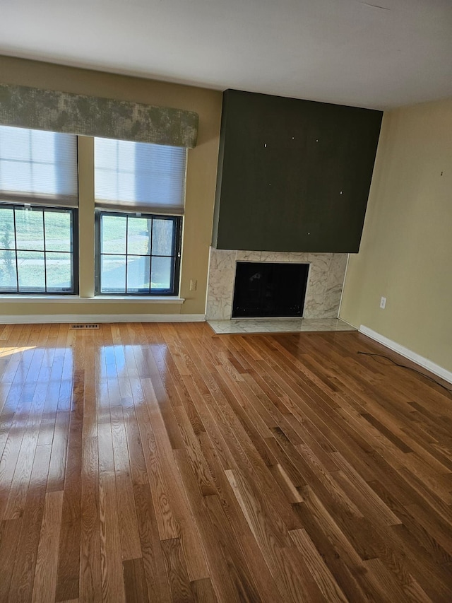 unfurnished living room featuring a high end fireplace and hardwood / wood-style flooring