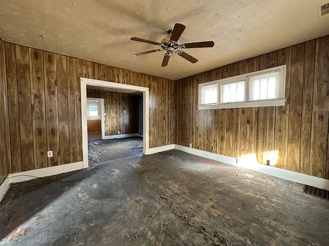 unfurnished room with ceiling fan and wood walls