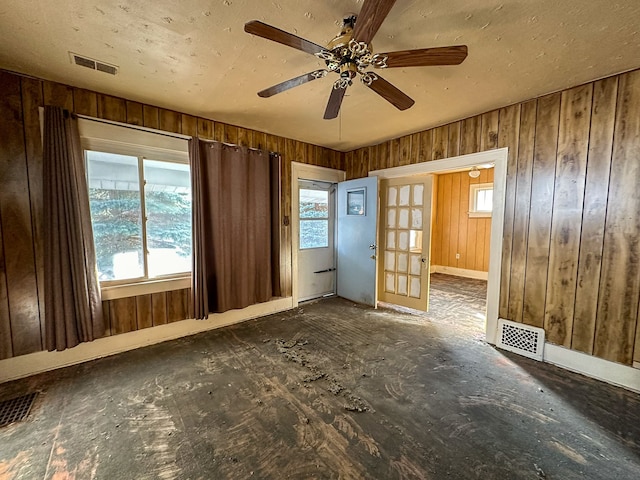 unfurnished room featuring ceiling fan, wood walls, and french doors