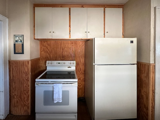 kitchen with white cabinets, wood walls, and white appliances