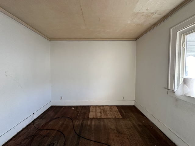 empty room with crown molding and dark wood-type flooring