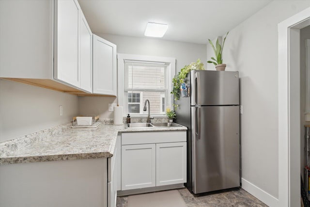 kitchen with white cabinets, stainless steel fridge, and sink