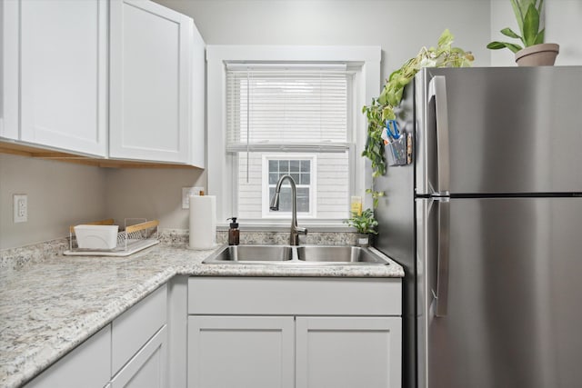 kitchen with stainless steel refrigerator, sink, and white cabinets