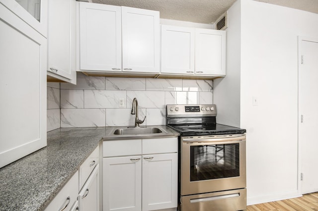 kitchen with electric stove, sink, light hardwood / wood-style flooring, a textured ceiling, and white cabinetry