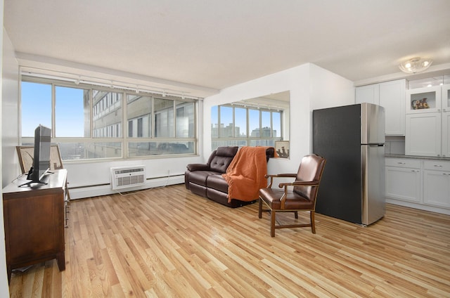 sitting room featuring an AC wall unit, light hardwood / wood-style flooring, and a baseboard radiator