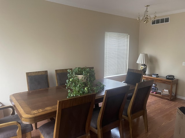 dining space featuring crown molding, dark hardwood / wood-style floors, and an inviting chandelier