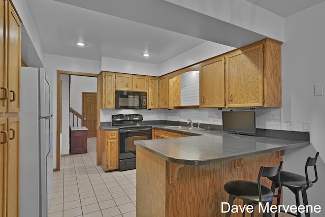 kitchen with a breakfast bar, black appliances, sink, tasteful backsplash, and kitchen peninsula