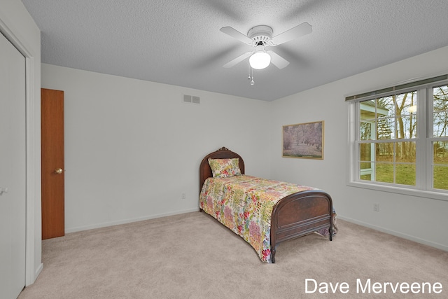 carpeted bedroom with ceiling fan and a textured ceiling