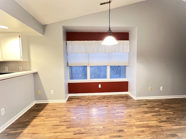 unfurnished dining area featuring lofted ceiling and light hardwood / wood-style flooring