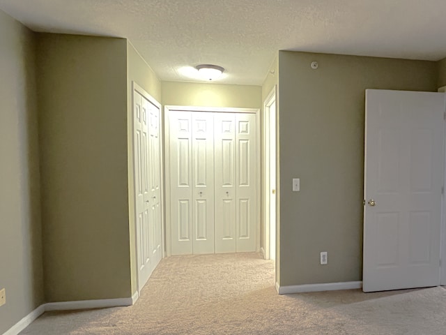 hallway with light carpet and a textured ceiling