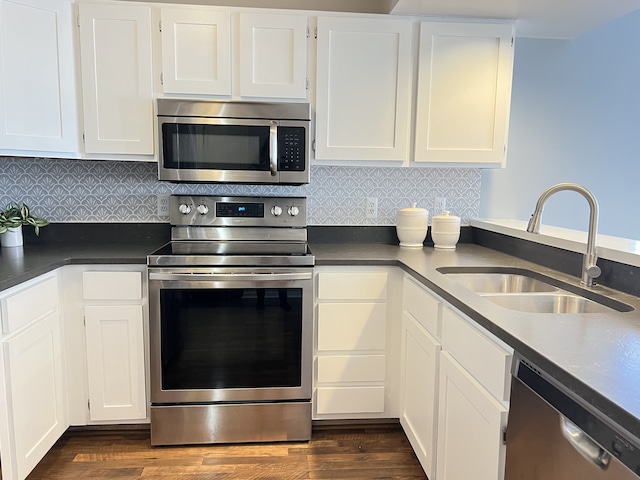 kitchen with sink, dark wood-type flooring, white cabinetry, stainless steel appliances, and tasteful backsplash