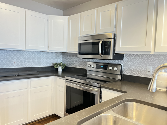 kitchen featuring appliances with stainless steel finishes, sink, white cabinets, and backsplash