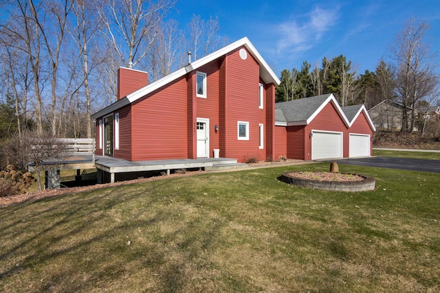 4243C Summerhill Rd, Traverse City, MI 49684 - view of property exterior with asphalt driveway, a chimney, a garage, a lawn, and a deck