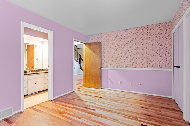 4243C Summerhill Rd, Traverse City, MI 49684 - unfurnished bedroom with wallpapered walls, light wood-style floors, and ensuite bath