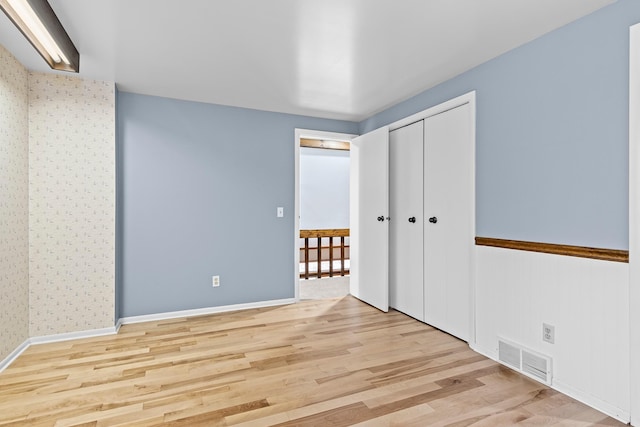 unfurnished bedroom with light wood-type flooring and a closet