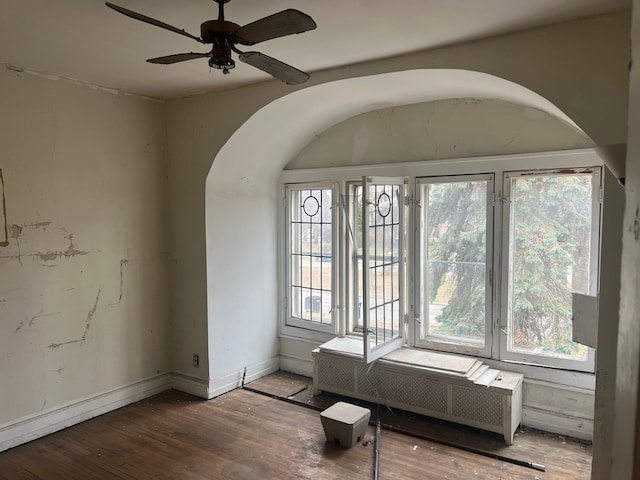 spare room featuring a wealth of natural light, radiator heating unit, ceiling fan, and wood-type flooring