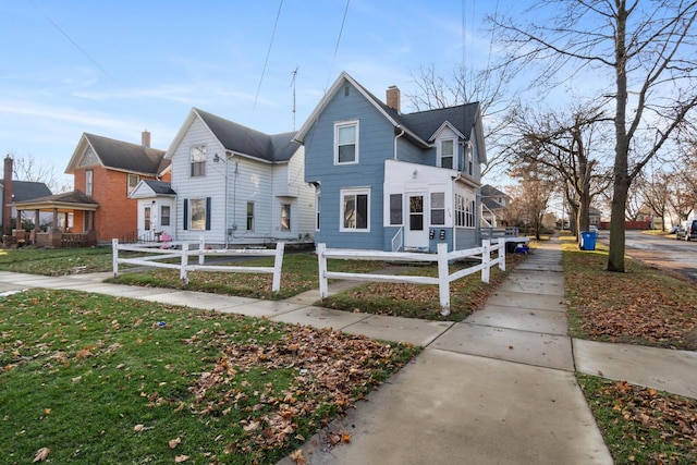 view of front facade with a sunroom, a fenced front yard, and a chimney