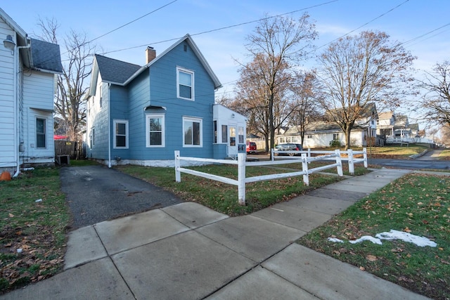 view of side of home featuring a shingled roof, central AC unit, a fenced front yard, and a chimney