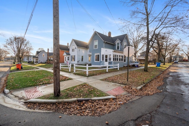 view of front facade featuring a residential view, a chimney, and fence