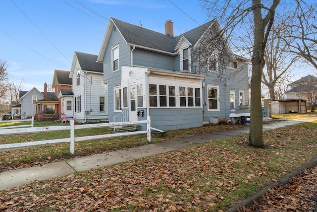 view of home's exterior featuring a fenced front yard, a chimney, and a shingled roof