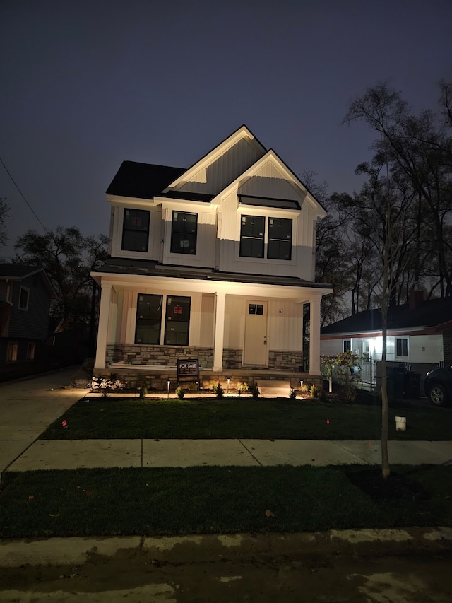 modern inspired farmhouse with board and batten siding, stone siding, and a porch