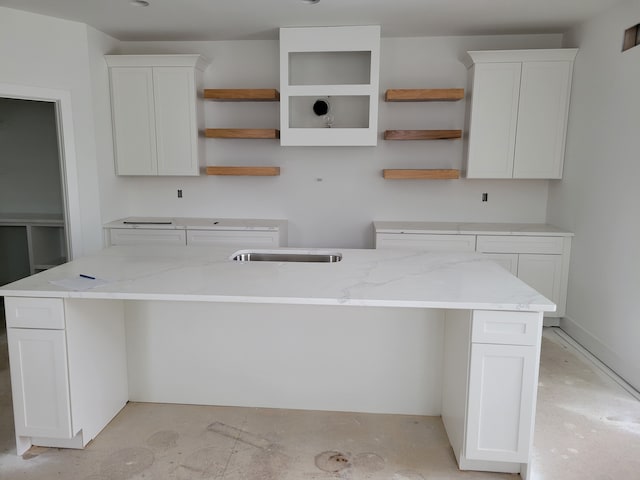 kitchen with white cabinetry and a center island with sink