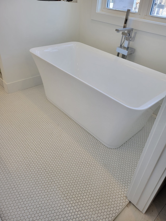 full bathroom featuring a wealth of natural light, a freestanding tub, and baseboards