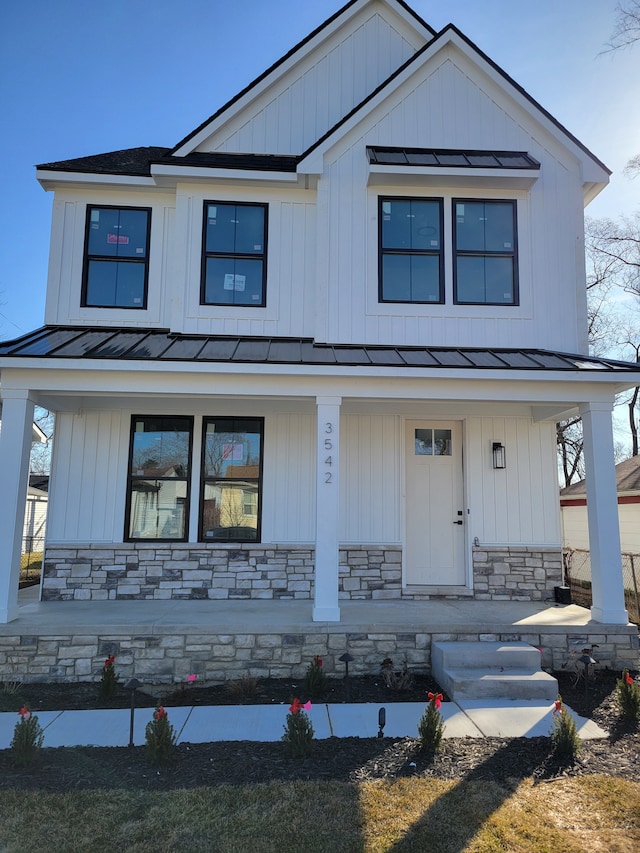 modern inspired farmhouse featuring metal roof, stone siding, covered porch, and a standing seam roof