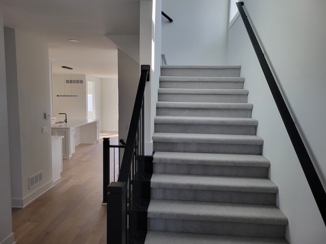 staircase featuring visible vents, baseboards, and wood finished floors