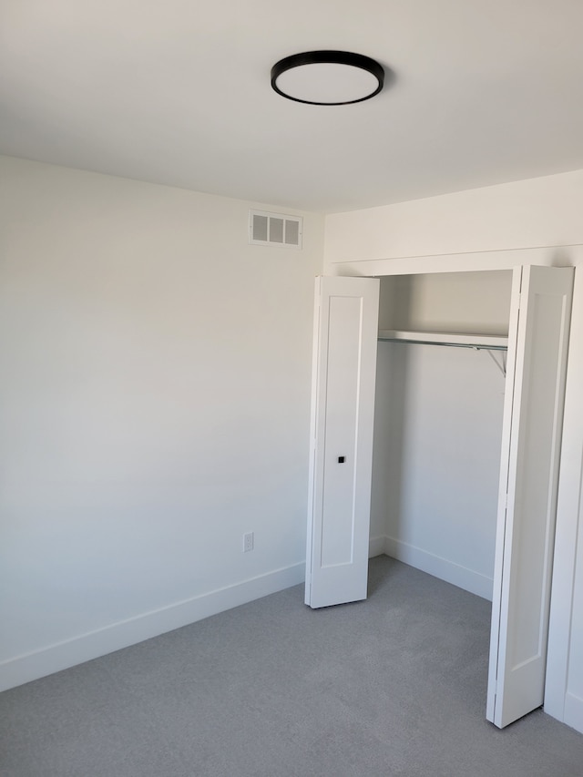 unfurnished bedroom featuring carpet flooring, baseboards, visible vents, and a closet